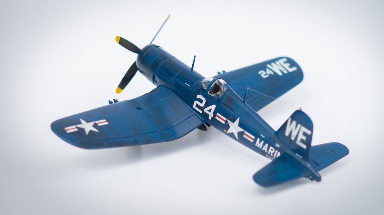 Close-up of a navy blue model airplane with military markings on a white background.
